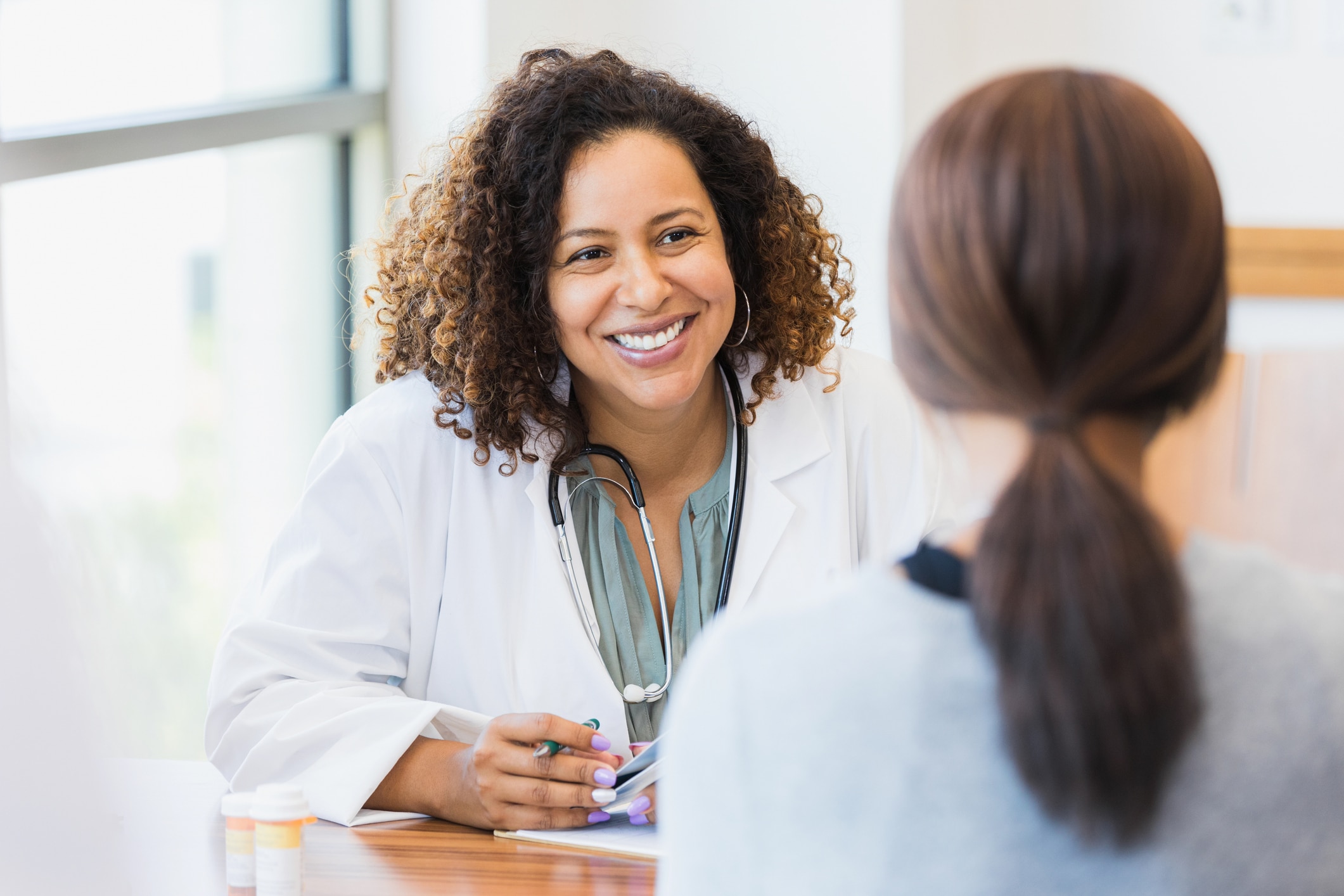 a doctor sitting at a desk talking to a patient