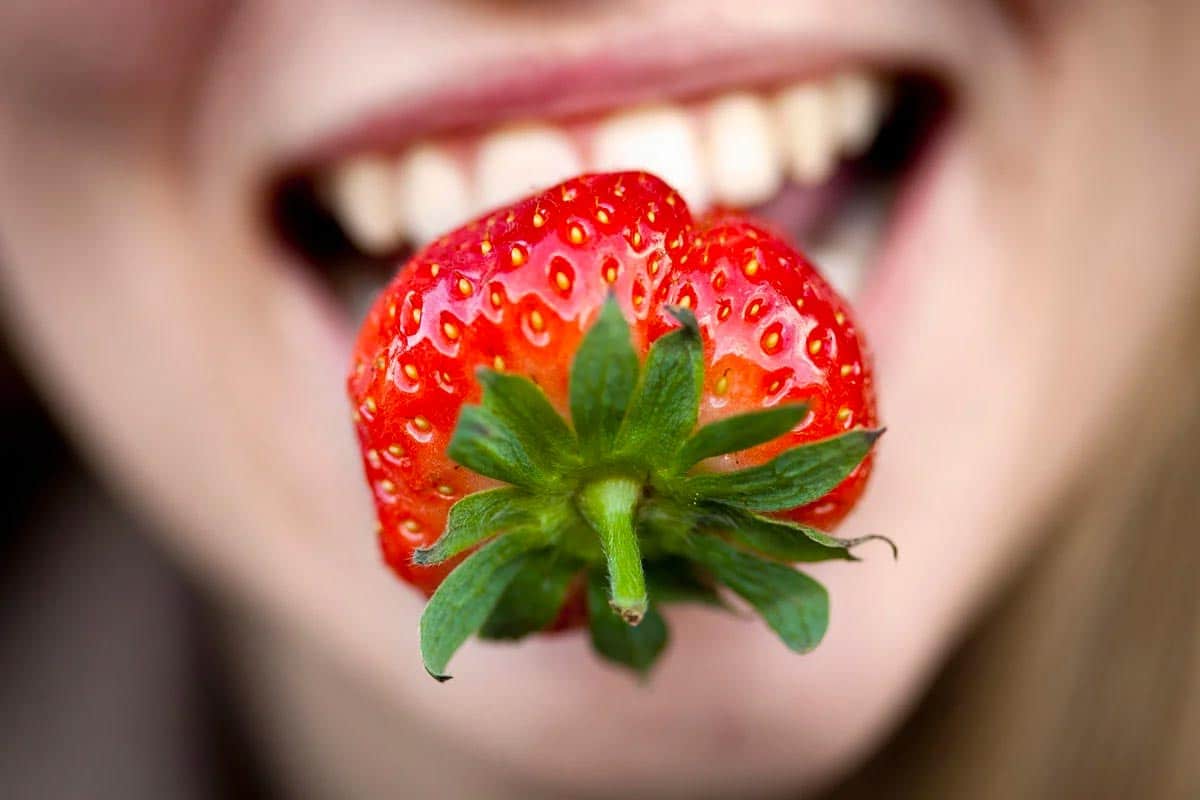 strawberry held between upper and lower lips