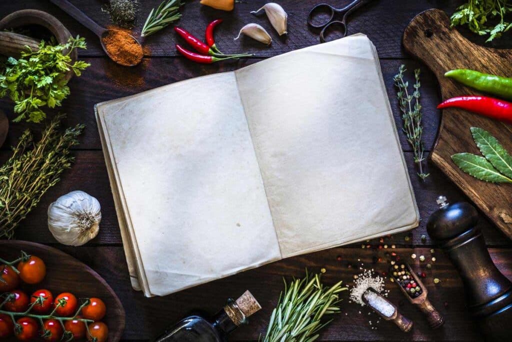 blank book on counter top with lots of vegetables surrounding it