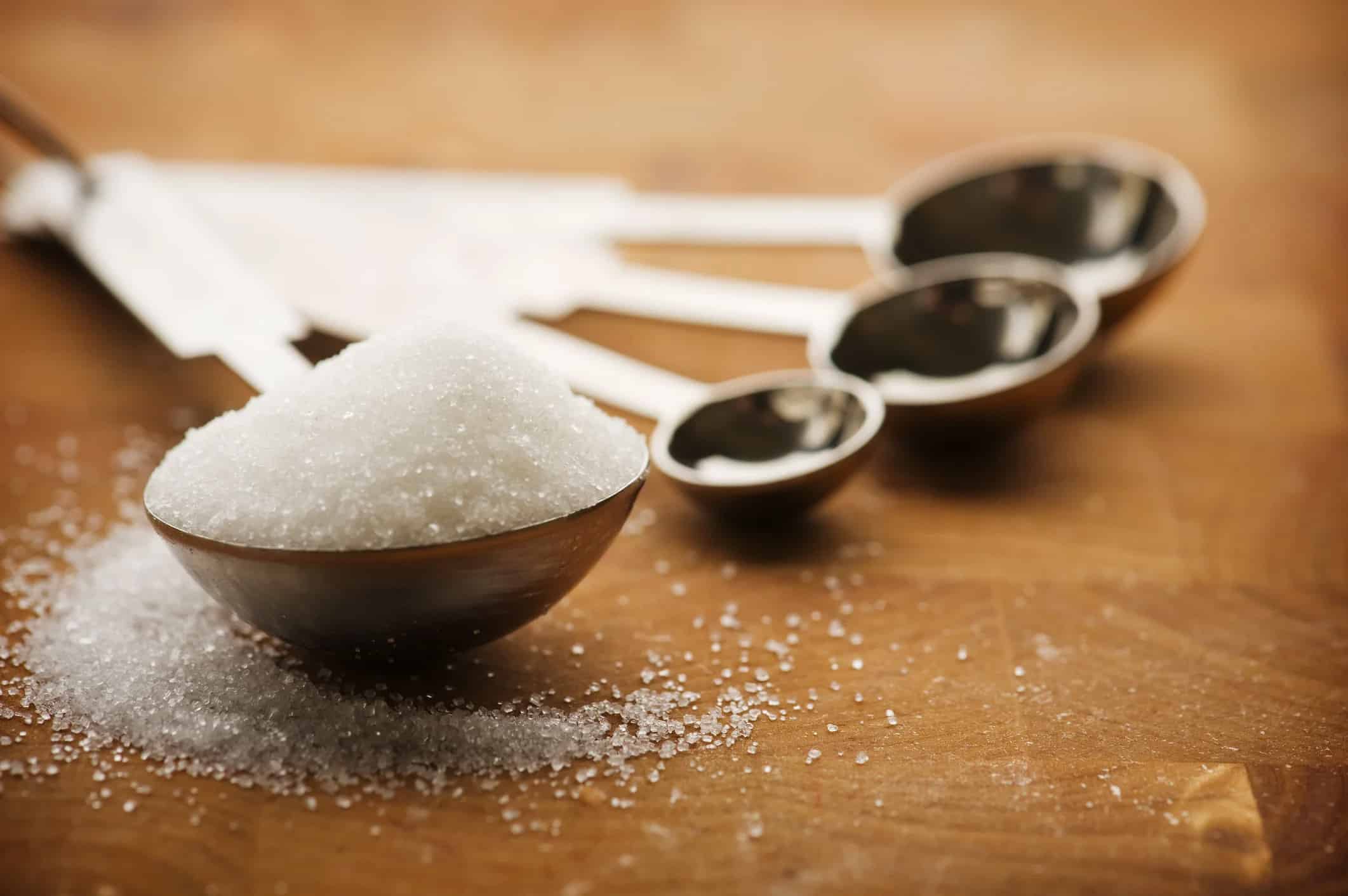 heaping tablespoon of sugar on a wooden counter top