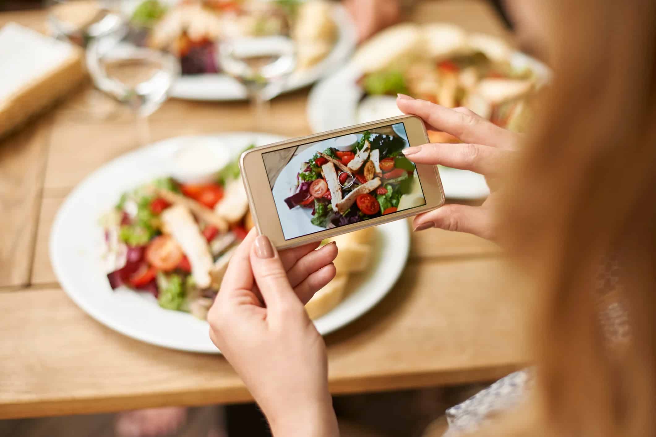 woman taking a photo of her healthy dinner plate of food