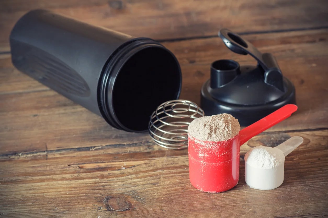 protein powder scoop next to empty water bottle