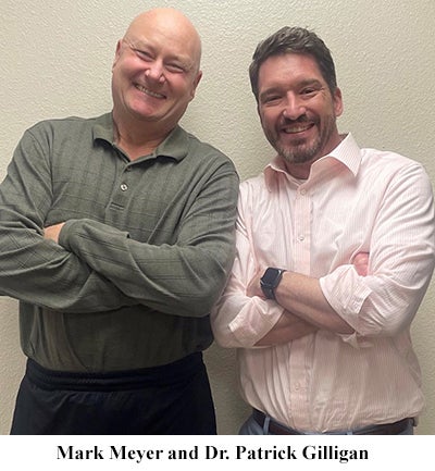 Two men standing together smilingDescription automatically generated