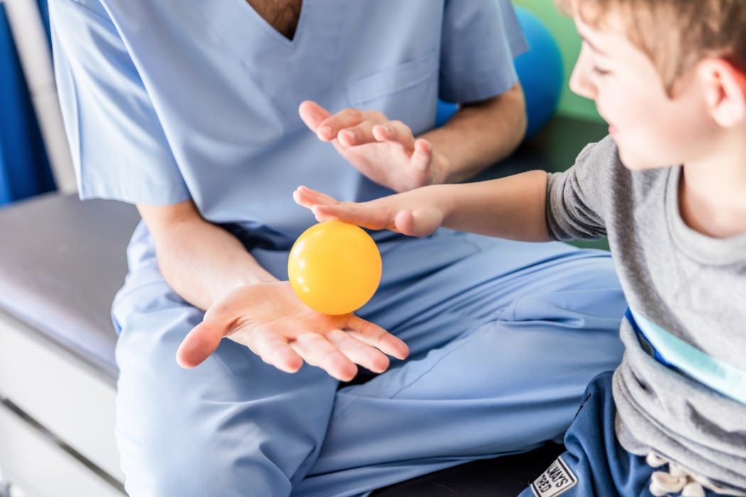 child doing occupational therapy with small yellow ball