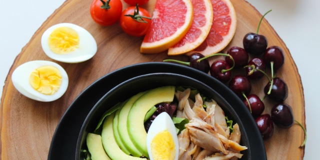 healthy plate of food featuring eggs, cherries, grapefruit, avocados, and meat