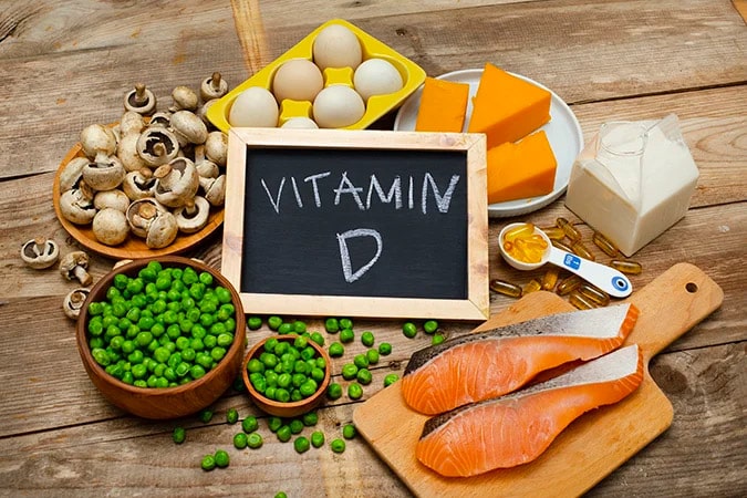 vitamin D written on a chalkboard in the middle of healthy meats and fruits