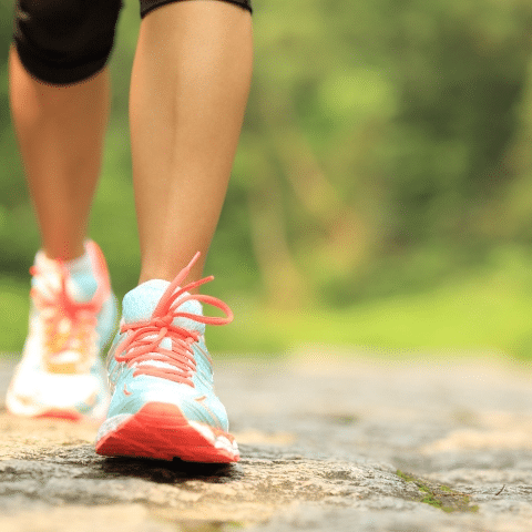 Close-up of a person walking on a paved path wearing colorful running shoes outdoors.