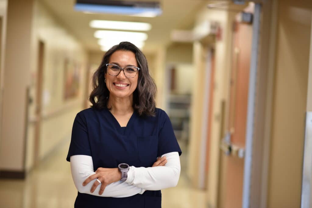 Female nurse smiling and crossing her arms.