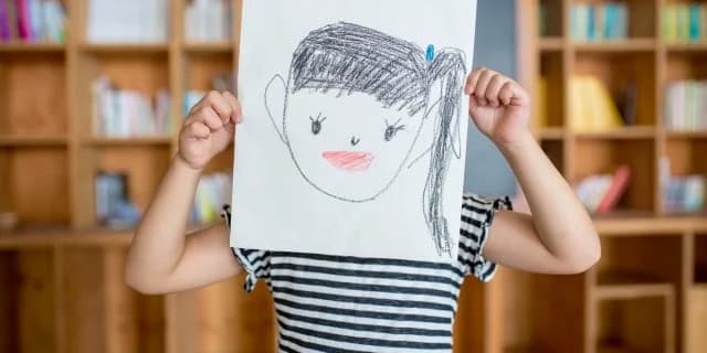 kid holding up drawing of herself
